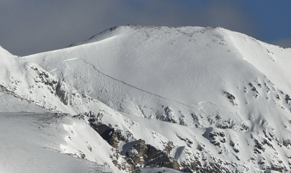 Looking at a large avalanche crown on a steep slope in the distance.