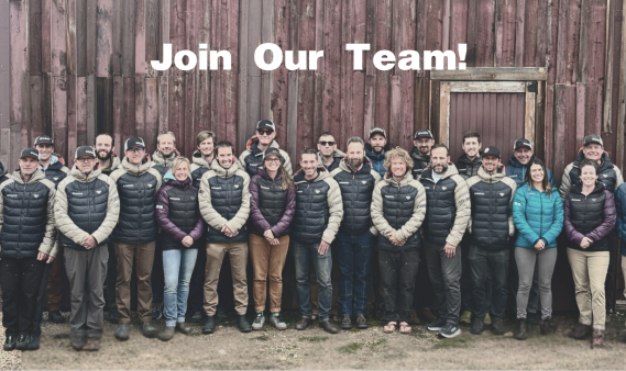 CAIC team posing in front of red barn wearing CAIC coats. 