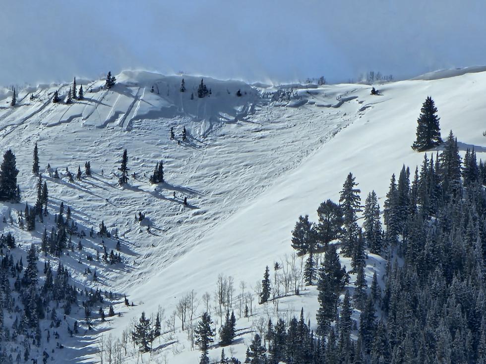 Close up of large avalanche near ridgeline on a steep slope.