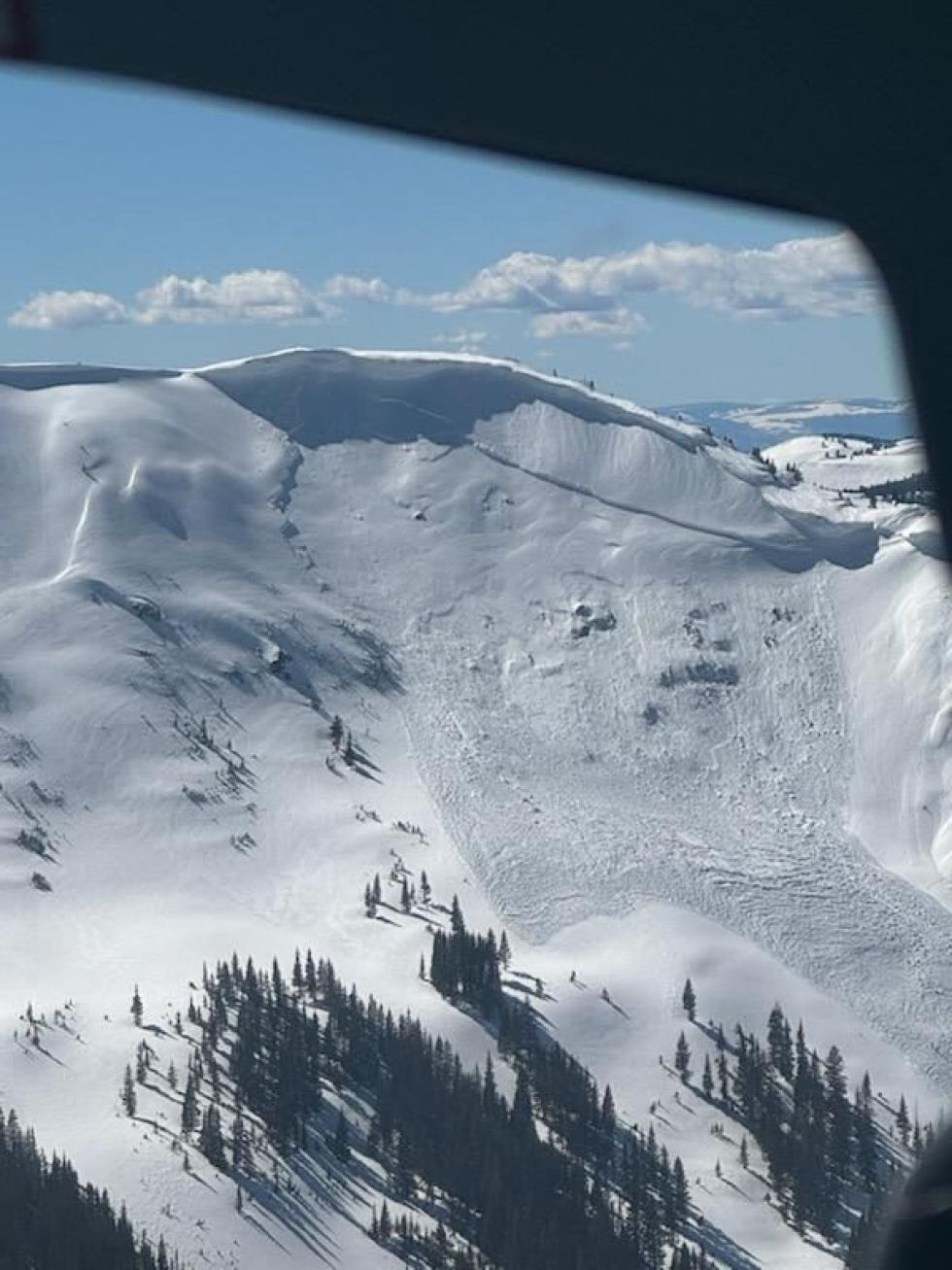 Large avalanche below a cornice on a steep snowy slope. 
