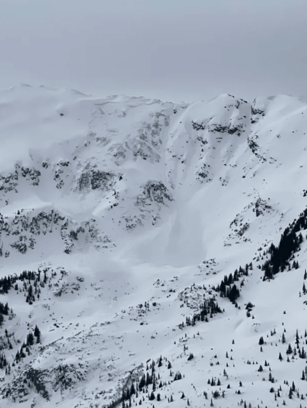 Large avalanche on a steep rocky mountain on a stormy day.